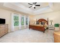 Bright main bedroom featuring a tray ceiling, plush carpeting, and large windows with natural light at 8 Queensland Ct, Durham, NC 27712