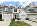 Townhome exteriors featuring garages and small landscaped lawns under a cloudy blue sky at 95 Little Leaf Lane Ln, Clayton, NC 27527