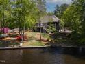 Waterfront home with tiered decks, lush landscaping, and dock access offering picturesque views of the serene lake at 955 Sagamore Dr, Louisburg, NC 27549