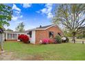 Cozy home with brick and siding, complemented by a screened-in porch and vibrant flowers at 1149 Us-701 Hwy, Four Oaks, NC 27524
