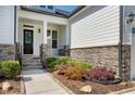 Inviting front porch with stone accents, landscaping, and a stylish front door at 1165 Saint Cloud Loop, Apex, NC 27523