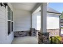 Cozy front porch with stone supports, white siding, and a view of the surrounding neighborhood at 1165 Saint Cloud Loop, Apex, NC 27523