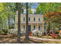Inviting yellow home with a welcoming front porch surrounded by beautiful trees and greenery at 1600 S Wade Ave, Garner, NC 27529