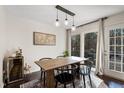 Bright dining room with modern lighting, a wooden table, black chairs, and a sliding glass door leading outdoors at 19 Lansgate Ct, Durham, NC 27713