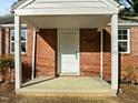 Close-up of the home's inviting covered front porch with brick facade at 203 W Pilot St, Durham, NC 27707