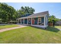 Blue home featuring a welcoming covered front porch, lush lawn and vibrant red front door at 211 Hargrove St St, Durham, NC 27701