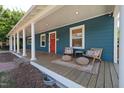 Inviting covered front porch with chairs, pillows, and a red front door at 211 Hargrove St St, Durham, NC 27701