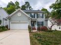 Inviting two-story home featuring an attached garage, manicured lawn, and quaint landscaping with a paved driveway at 2424 Horizon Hike Ct, Raleigh, NC 27603