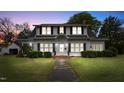 Charming two-story home with black shutters, landscaped yard, and inviting front entrance at dusk at 305 N Ellis Ave, Dunn, NC 28334