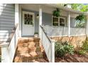 Close up of the front porch featuring brick stairs leading up to a white door and railing at 313 Dunhagan Pl, Cary, NC 27511