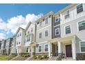 Townhome exteriors showcase varying color palettes and designs with manicured lawns and covered entrances at 5217 Invention Way, Raleigh, NC 27616