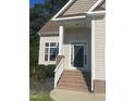 Elegant home entrance with brick steps, white railing, and a decorative front door at 66 Saddle Ln, Lillington, NC 27546