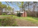 Quaint brick home featuring a chimney, partially wooded lot and fresh green lawn at 6702 Huntsboro Rd, Oxford, NC 27565