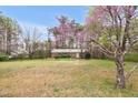 Serene view of a single-story brick home surrounded by lush greenery and flowering trees at 6702 Huntsboro Rd, Oxford, NC 27565