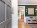 View of foyer leading to kitchen with stylish green accent wall, chandelier, and hardwood floors at 6909 Clear Sailing Ln, Raleigh, NC 27615