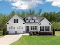 Beautiful white two-story home with a three-car garage, manicured lawn, and lovely landscaping at 9220 Yardley Town Dr, Wake Forest, NC 27587