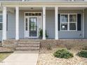 Covered front porch features classic white columns and a modern glass-paneled front door and low maintenance landscaping at 96 Ada Cir, Selma, NC 27576