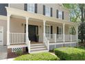 Inviting covered front porch with white railing, black door, and manicured landscaping at 102 Parkbranch Ln, Cary, NC 27519