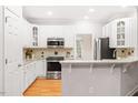 Well-lit kitchen features white cabinets, stone countertops, and stainless steel appliances at 103 Caymus Ct, Cary, NC 27519