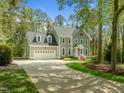 View of a two-story house with an attached garage and a long driveway surrounded by lush greenery at 105 Toynbee Pl, Chapel Hill, NC 27514