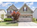 Two story home with green siding, stone accents, a two-car garage and beautifully landscaped front yard at 1109 Forest Willow Ln, Morrisville, NC 27560