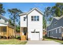 Well-maintained white home with a front-facing garage, wood stairs, and a tidy front yard at 1207 Chaney Rd, Raleigh, NC 27606