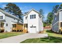 Charming white two-story home with a well-manicured lawn, front-facing garage, and wooden steps at 1207 Chaney Rd, Raleigh, NC 27606