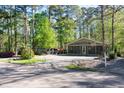 Exterior view of a green home in a wooded area with gravel landscaping and street access at 142 Blackhawk Dr, Louisburg, NC 27549