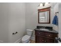 Elegant half bathroom features a dark wood vanity, black countertop, and decorative mirror at 1512 Piazzo Ct, Apex, NC 27502