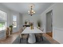 Formal dining room with a white table, elegant chandelier, wainscoting and large windows at 1512 Piazzo Ct, Apex, NC 27502