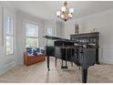 Bright living room with a piano, bay windows, neutral color palette and chandelier at 1512 Piazzo Ct, Apex, NC 27502