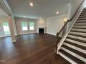 Open living room showcasing hardwood floors, a cozy fireplace, and stairs with a wooden railing at 1572 Bright Coral Trl, Wendell, NC 27591