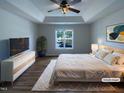 Bright main bedroom with tray ceiling, ceiling fan, and a large window overlooking the front yard at 312 Sarazen Dr, Clayton, NC 27527