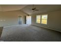 Open-concept living space with plush carpeting, a modern ceiling fan, and natural light streaming through large windows at 48 Pate Landing Dr, Selma, NC 27576