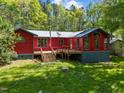 Expansive backyard featuring a lush lawn, wooden deck, and a charming red house at 5401 Friends School Rd, Durham, NC 27705