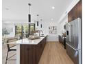 Modern kitchen island with quartz countertops, brown cabinets, stainless steel appliances, with wood flooring at 615 W Peace St # 201, Raleigh, NC 27605