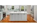 Bright kitchen with white cabinets, stainless steel appliances, a large island, and hardwood floors at 6216 Valley Estates Dr, Raleigh, NC 27612