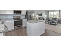 Modern kitchen features white cabinets, stainless steel appliances, granite counters, and an island, adjacent to an inviting living area at 634 Silverado Sunset Loop, Wendell, NC 27591