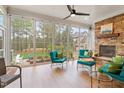 Relaxing sunroom featuring a stone fireplace, comfortable seating, ceiling fan, and large windows with views of the yard at 749 Golfers Vw, Pittsboro, NC 27312