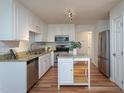 Modern kitchen features white cabinets, stainless steel appliances, granite countertops and an island at 8000 Elderson Ln, Raleigh, NC 27612