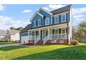 A charming two-story home with blue siding, a welcoming front porch, and a lush green lawn at 9204 Cub Trl, Raleigh, NC 27615