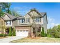 Inviting home featuring a stone and siding facade, a two-car garage, and professionally landscaped front yard at 936 Regency Cottage Pl, Cary, NC 27518