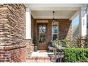 Charming front porch with stone accents, decorative wreath, and cozy seating area with a brick pathway at 936 Regency Cottage Pl, Cary, NC 27518