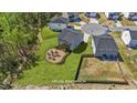 A backyard features a circular patio, fire pit, seating area, and lush landscaping; a virtual renovation at 95 Shady Creek Trl, Garner, NC 27529