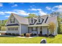 Two-story home featuring gray siding, a black roof, and a covered front porch with decorative columns at 1077 Williams-White Rd, Zebulon, NC 27597