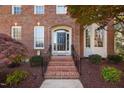 Close-up of the home's entryway featuring a black front door, brick steps, and manicured landscaping at 125 Kelekent Ln, Cary, NC 27518