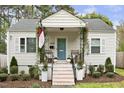Welcoming front of a home with a porch featuring seating, flower pots, and a blue-painted front door at 2008 Reaves Dr, Raleigh, NC 27608