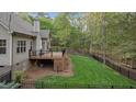 Fenced backyard features lush lawn, treed perimeter, and a spacious deck with black railings at 2204 Secluded Oaks Ct, Wake Forest, NC 27587