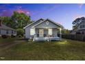 Charming one-story home featuring a cozy front porch, swing, and professional landscaping illuminated at twilight at 303 E J St, Erwin, NC 28339