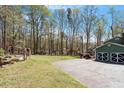 Spacious backyard with mature trees and a driveway leading to a two-car garage at 3418 Carriage Trl, Hillsborough, NC 27278